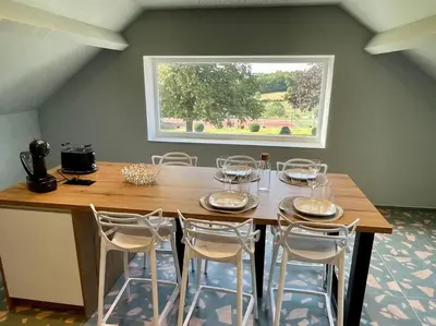 a dining room table with chairs and a large window at Gite Pays de Herve - Emeraude in Battice