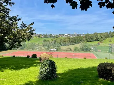 a field with a tennis court in the distance at Gite Pays de Herve - Emeraude in Battice