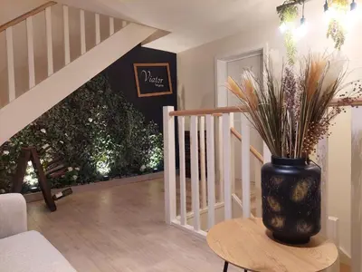 a vase with a plant on a table next to a staircase at Viator Holidayhome in Tongeren