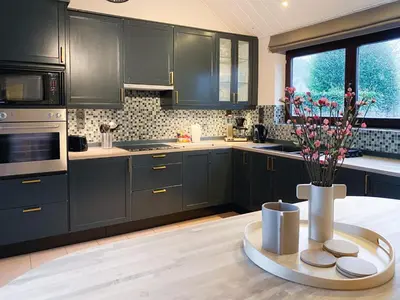 a kitchen with black cabinets and a table with flowers at 8P 4B Beautiful Villa with swimming pool in Zonhoven in Genk