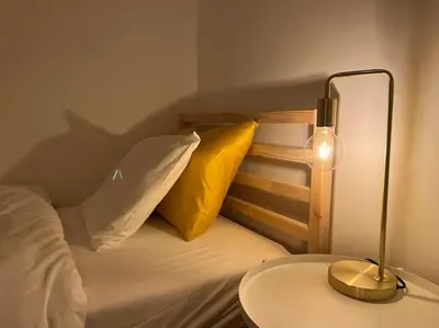 a bed with a yellow pillow and a lamp on a table at Boldermountain Guesthouse in Heusden - Zolder