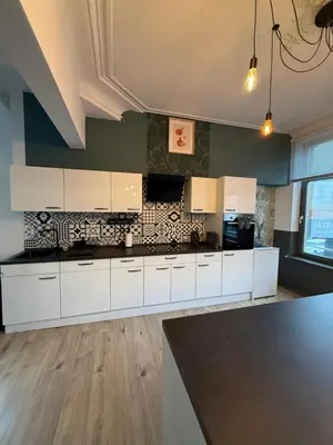 a kitchen with white cabinets and a black counter top at Duplex dans le centre d'Heusy in Verviers