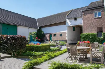 a patio with chairs and a table in front of a building at B&B De Oude Winning in Riemst
