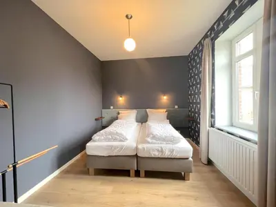 a bedroom with two beds and a large window at Woonhuys in Riemst