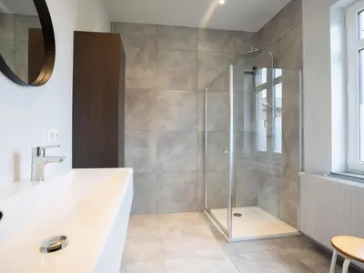 a bathroom with a shower with a tub and a sink at Woonhuys in Riemst
