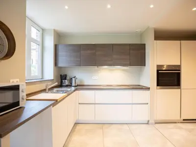 a kitchen with white cabinets and a clock on the wall at t Bakhuys in Riemst
