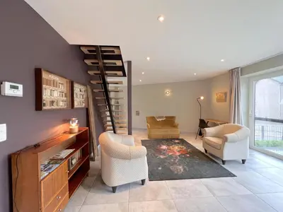 a living room with a spiral stair case and chairs at t Bakhuys in Riemst