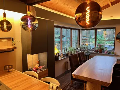 a dining room with a wooden table and some lights at Vakantiechalet voor 4 plus 2 met sauna in Lanaken