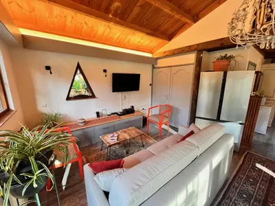 a living room with a white couch and a kitchen at Vakantiechalet voor 4 plus 2 met sauna in Lanaken