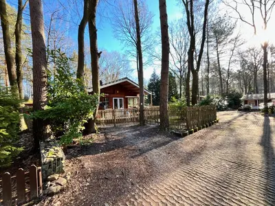 a house in the woods with a fence at Vakantiechalet voor 4 plus 2 met sauna in Lanaken