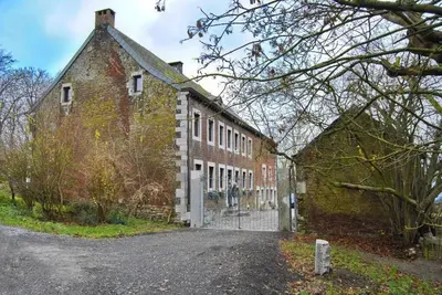 an old brick building with a gate in front of it at Le Chat Roi - Charneux in Herve