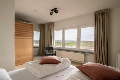 a bedroom with a bed and a large window at Maas Suites - The River House with private sauna in Lanaken