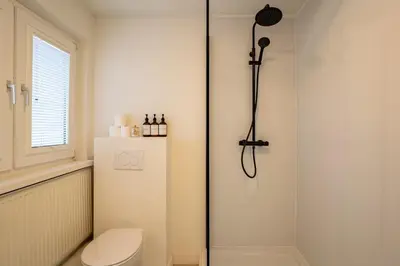 a white bathroom with a shower and a toilet at Maas Suites - The River House with private sauna in Lanaken