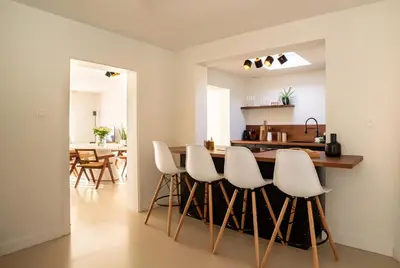 a kitchen with white chairs and a kitchen island at Maas Suites - The River House with private sauna in Lanaken