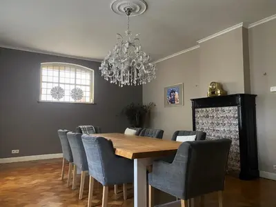 a dining room with a table with chairs and a chandelier at B&B Huis Spaas in Pelt