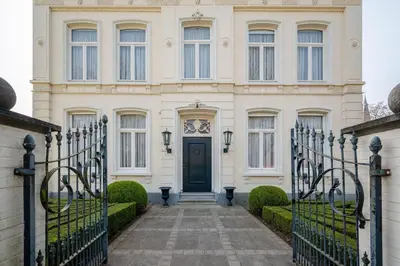 a large white house with a blue door at B&B Huis Spaas in Pelt