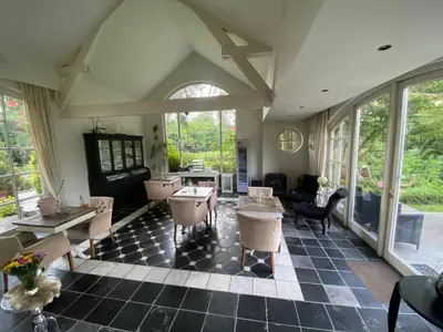 a living room with tables and chairs and windows at B&B Huis Spaas in Pelt