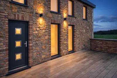 a brick house with a deck at night at Spa-Francorchamps - Jahlay - Maison 6p de caractère - Famille - Ardennes - Nature in Jalhay