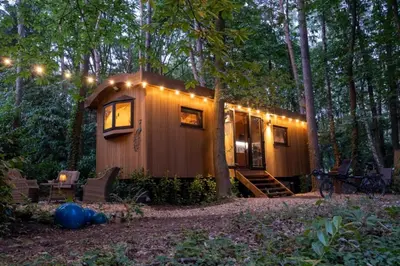 a small cabin in the woods with lights on it at Pipowagen de Pauw in de bossen van Belgisch Limburg nabij Maastricht in Lanaken