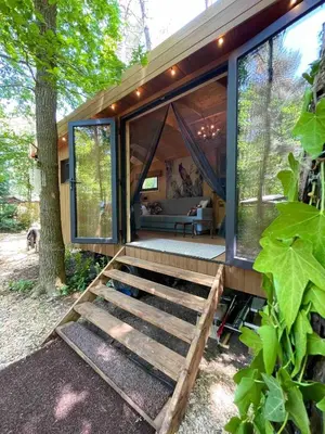 a modern house with glass doors and a porch at Pipowagen de Pauw in de bossen van Belgisch Limburg nabij Maastricht in Lanaken