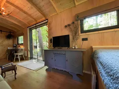 a bedroom with a bed and a tv in a room at Pipowagen de Pauw in de bossen van Belgisch Limburg nabij Maastricht in Lanaken