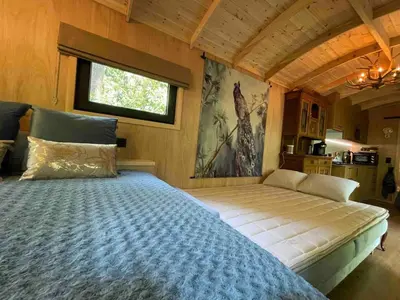 a bedroom with a large bed in a room at Pipowagen de Pauw in de bossen van Belgisch Limburg nabij Maastricht in Lanaken