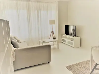 a white living room with a couch and a tv at COCONUT MILK in Liège
