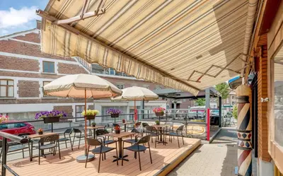 an outdoor patio with tables and chairs and umbrellas at Café René Borgloon in Borgloon