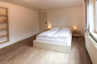 a white bed in a white room with a window at Aan de bosrand in Oudsbergen