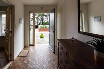 a hallway with a dresser and a mirror and a door at Aan de bosrand in Oudsbergen
