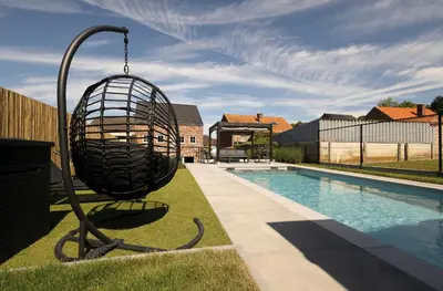 a swing in a yard next to a swimming pool at Vakantiewoning Het Kwartelnest Mettekoven (Heers) in Heers