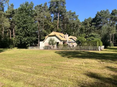 a house in a field with a fence at De Lelie in Rekem