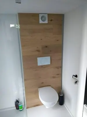 a bathroom with a toilet and a wooden wall at Côté jardin in Dison