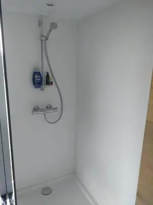 a shower in a bathroom with a white wall at Côté jardin in Dison