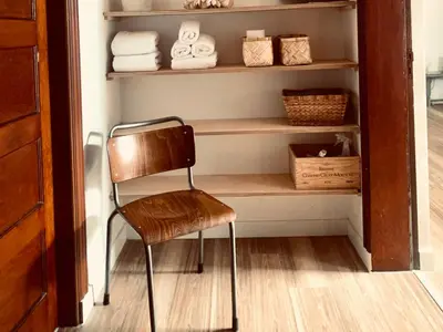 a chair sitting in front of a shelf with towels at Zolder appartement Le Grenier in Dilsen-Stokkem
