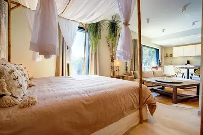 a bedroom with a canopy bed and a living room at La Bohème in Liège
