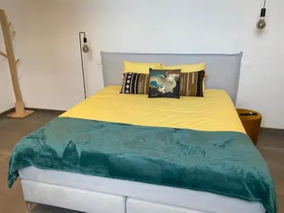 a bed with a yellow and blue blanket on it at Les Quais de la Vesdre in Verviers