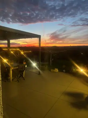 a sunset from a patio with a table and lights at Le calme de la prairie de liège in Liège