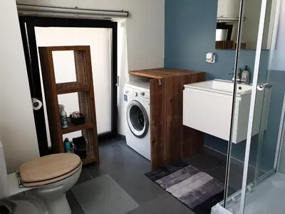 a bathroom with a washing machine and a washer at Het Zonnetje -Vakantiewoning en Bed and Breakfast in Dilsen-Stokkem