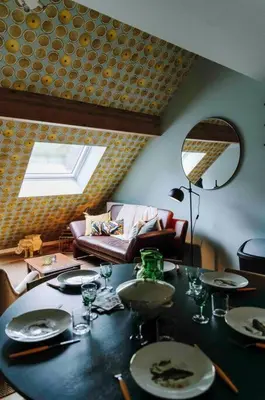 a dining room with a table and a couch at L’écrin vintage - Hors Château & Marches de Bueren in Liège