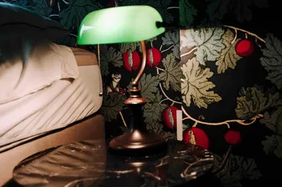 a green lamp sitting on a table next to a bed at L’écrin vintage - Hors Château & Marches de Bueren in Liège