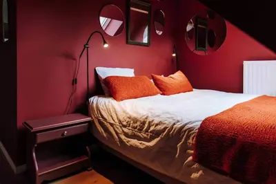 a red bedroom with a bed with orange pillows at L’écrin vintage - Hors Château & Marches de Bueren in Liège