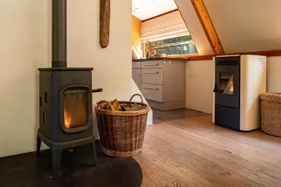a wood stove in a kitchen with a basket at Boshuisje Rekem - Flora in Lanaken