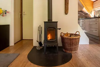 a wood stove in a kitchen with a basket at Boshuisje Rekem - Flora in Lanaken