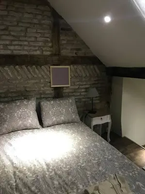 a bedroom with a bed and a brick wall at Petite maison Liégeoise «la cabane de Liège» in Liège