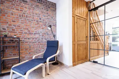 a room with a brick wall and a blue chair at Li Mohone in Donceel