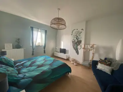 a bedroom with a blue bed and a couch at Au saut du Train in Remicourt