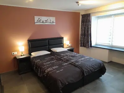 a bedroom with a large bed with two night stands and two lamps at Chez Francis in Verviers