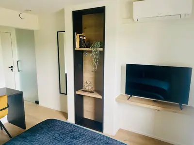 a living room with a tv and a bed in a room at Inova - Comfort Room with Private Bathroom and Shared Facilities in Hasselt