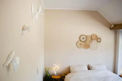 a white bedroom with a bed and some hats on the wall at Domaine des Arches in Soumagne